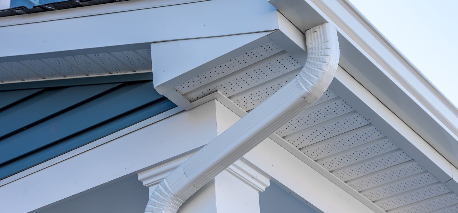 White seamless gutter and downspout installed along a home&rsquo;s roofline to direct rainwater away from the siding and foundation.