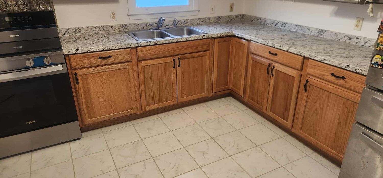 A kitchen with light wood cabinets, granite countertops, stainless steel appliances, and white tile flooring under a double stainless steel sink.