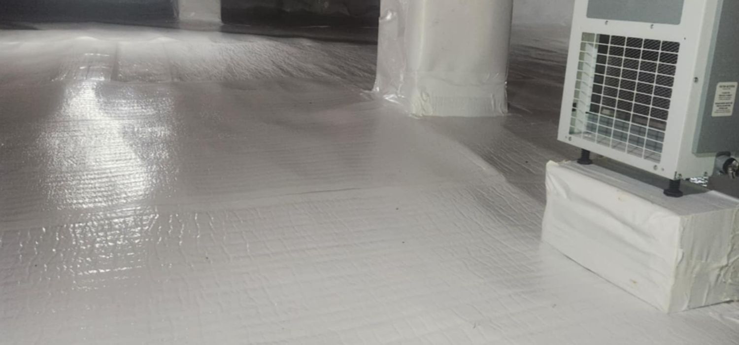 Clean, sealed crawl space with white vapor barrier and dehumidifier installed as part of a professional waterproofing and moisture control system.